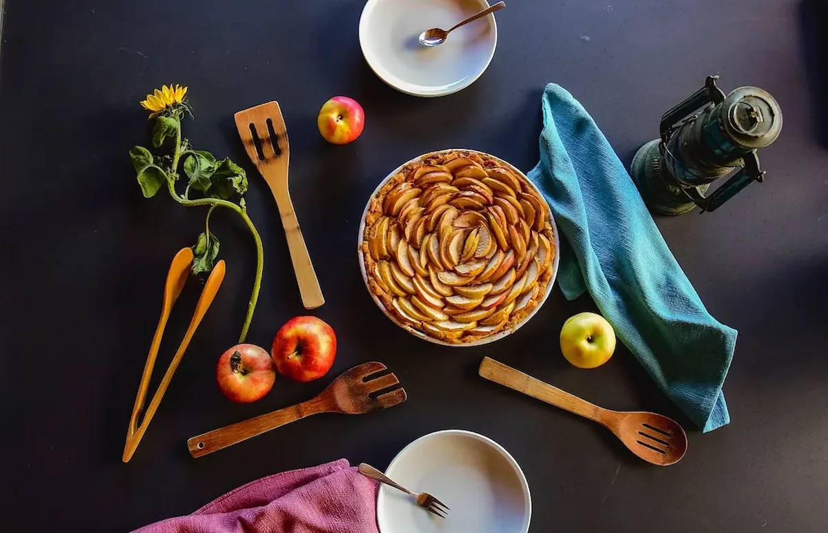 An apple pie surrounded by apples and cooking utensils, representing the need for a precise startup definition in the Venture Client Model.